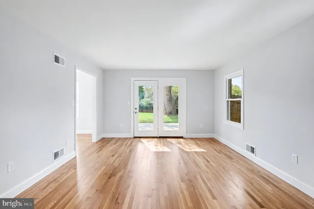 an empty room with wooden floor and windows