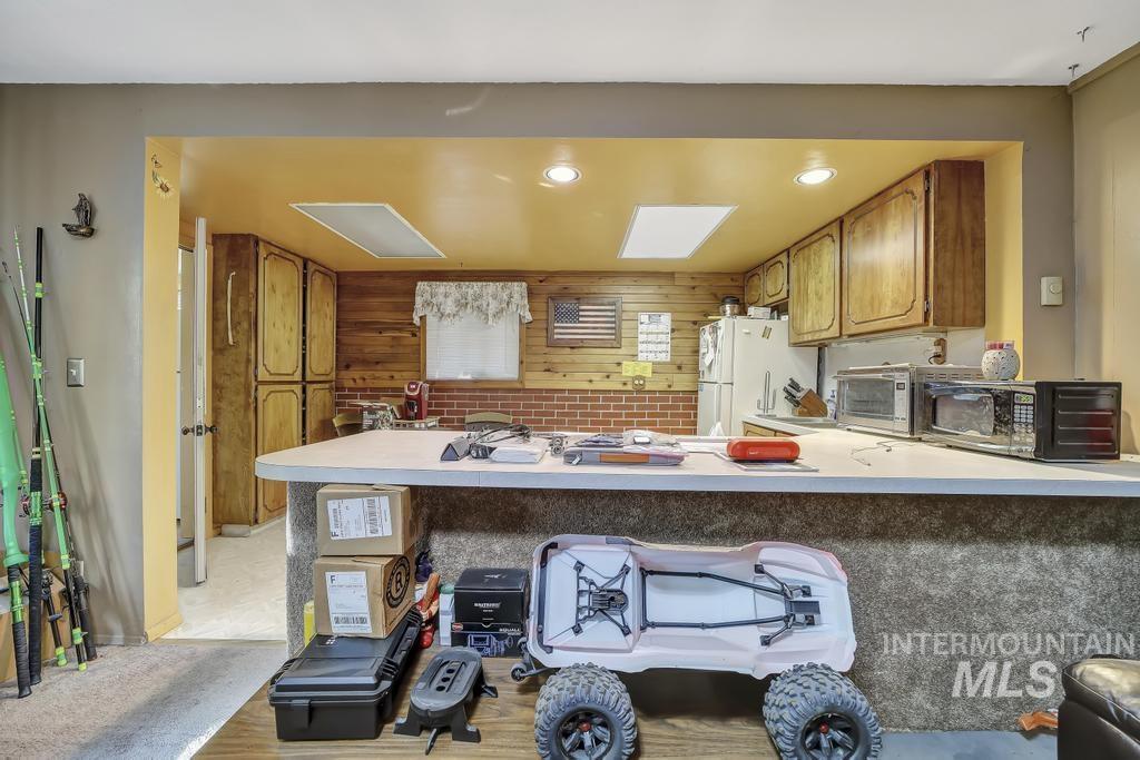 111 2nd Street Rupert, ID 83350 - Photo 20 of 45 Kitchen area featuring a breakfast bar with a light-toned countertop, wood-paneled walls, brick backsplash, and recessed lighting