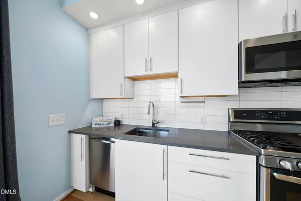 a kitchen with refrigerator a microwave a sink and cabinets