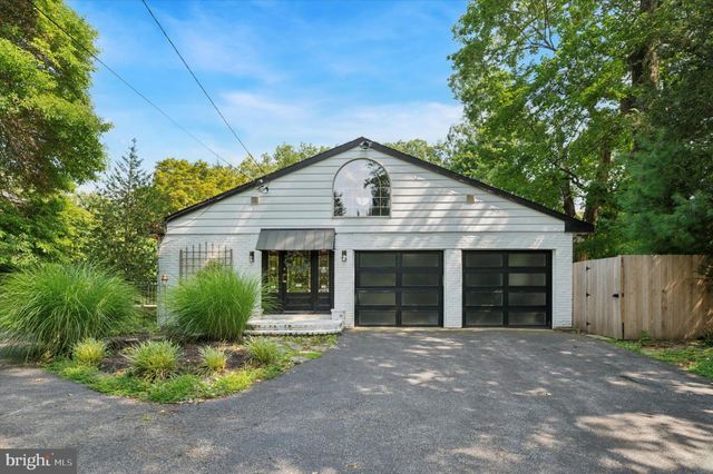 a view of a house with a small yard plants and a large tree