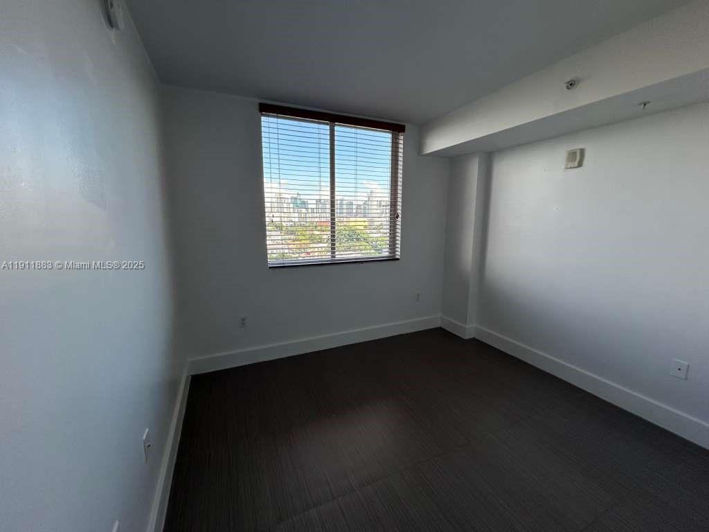219 Northwest 12th Avenue, Unit 1002 Miami, FL 33128 - Photo 11 of 15 an empty room with wooden floor and windows