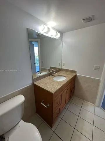 a bathroom with a granite countertop sink a toilet and a mirror