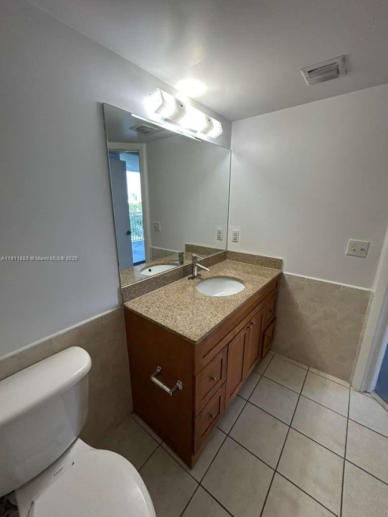 219 Northwest 12th Avenue, Unit 1002 Miami, FL 33128 - Photo 15 of 15 a bathroom with a granite countertop sink a toilet and a mirror
