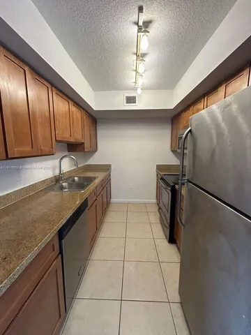 a kitchen with stainless steel appliances granite countertop a sink refrigerator and cabinets