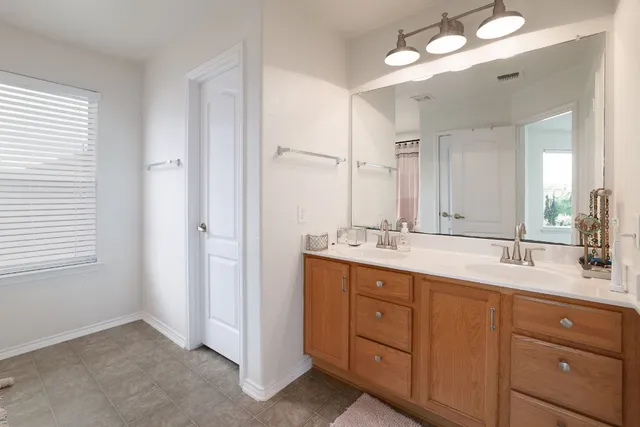 a bathroom with double vanity sink a vanity a lamp and a mirror