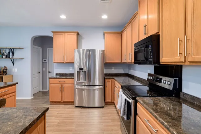 a kitchen with stainless steel appliances granite countertop a refrigerator a stove a sink and a microwave