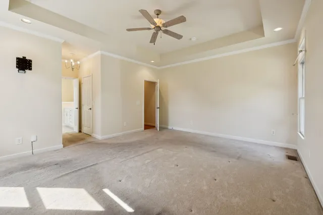 an empty room with a ceiling fan and carpet