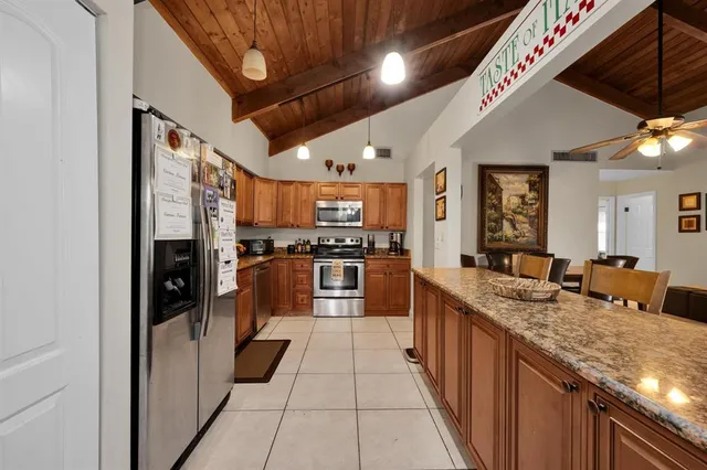a large kitchen with stainless steel appliances granite countertop a large counter top a stove and a refrigerator