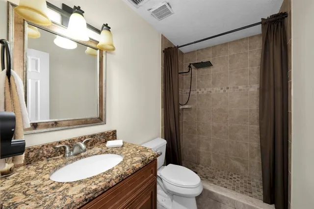 a bathroom with a granite countertop sink toilet mirror and shower