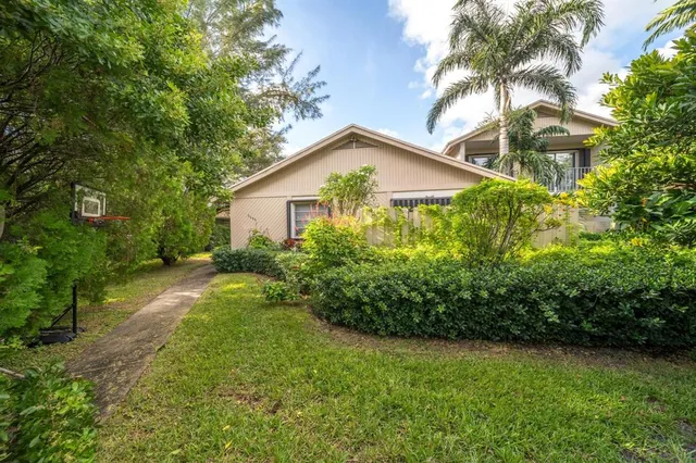 a view of a house with a small yard and palm trees