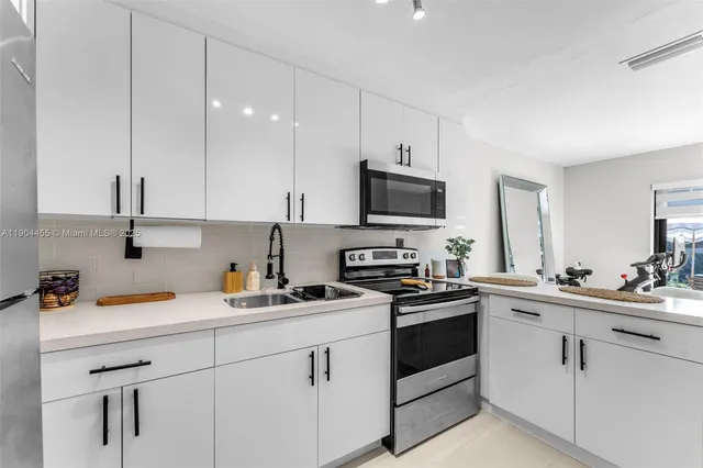 a kitchen with white cabinets stainless steel appliances and sink
