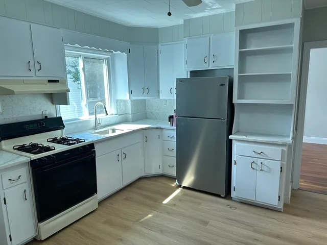 a kitchen with a stove cabinets and wooden floor