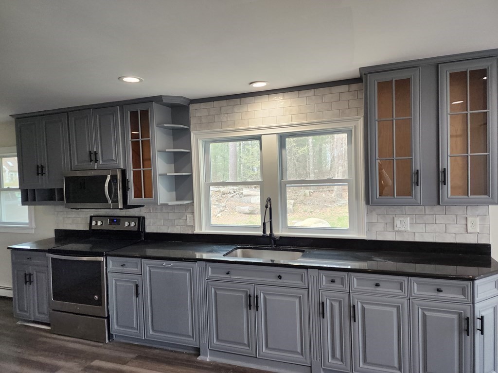 81 Onset Avenue Wareham, MA 02532 - Photo 23 of 42 a kitchen with granite countertop white cabinets sink and stainless steel appliances