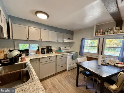 a kitchen with a stove a sink dishwasher a dining table and chairs with wooden floor