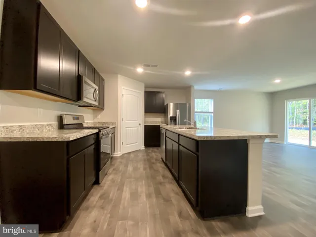 a large kitchen with stainless steel appliances kitchen island granite countertop a large counter top and wooden floors