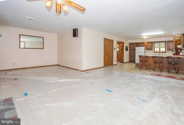 an empty room with chandelier fan and windows