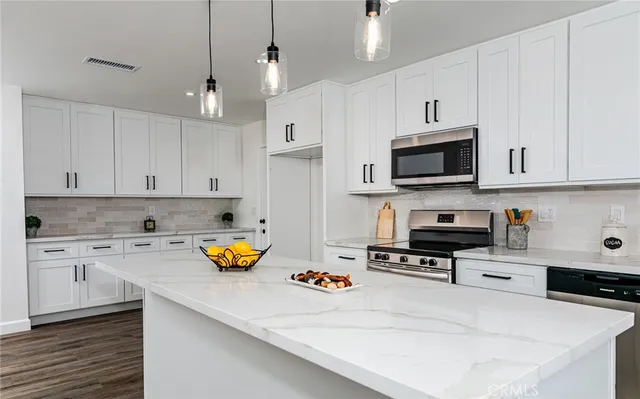a kitchen with stainless steel appliances a stove a sink and white cabinets