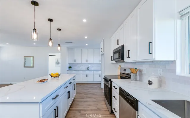 a kitchen that has a lot of cabinets in it with stainless steel appliances granite countertop a sink a stove and a wooden floors