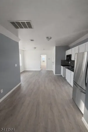 a view of a kitchen with a sink refrigerator cabinets and a window