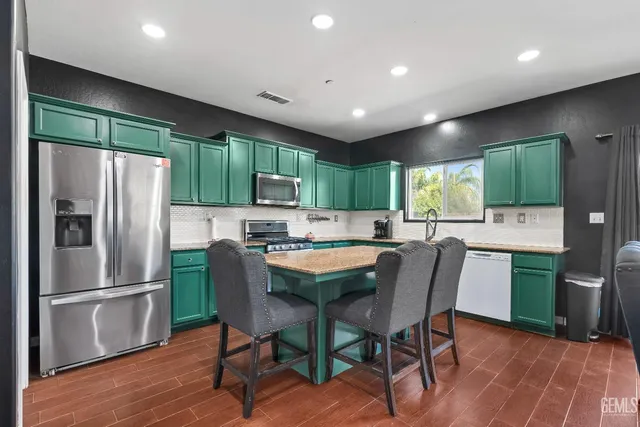 a kitchen with stainless steel appliances granite countertop a refrigerator a sink dishwasher a stove and a refrigerator with wooden floor