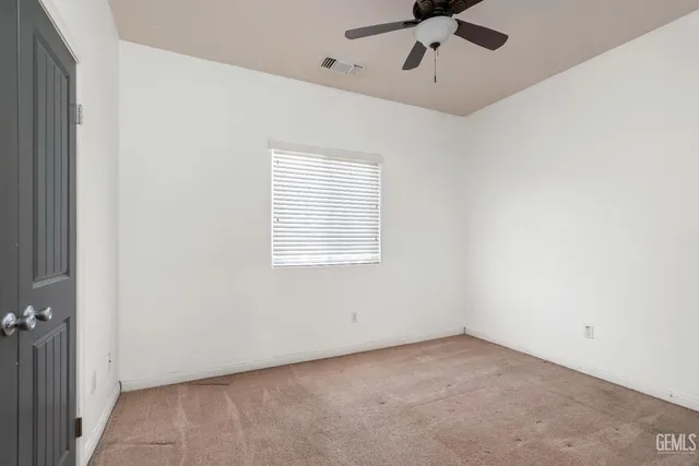 an empty room with a ceiling fan and window