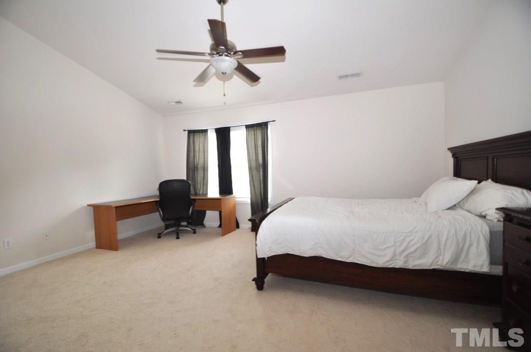 2529 Dality Drive Raleigh, NC 27604 - Photo 14 of 20 a bedroom with a bed a chandelier and a dresser