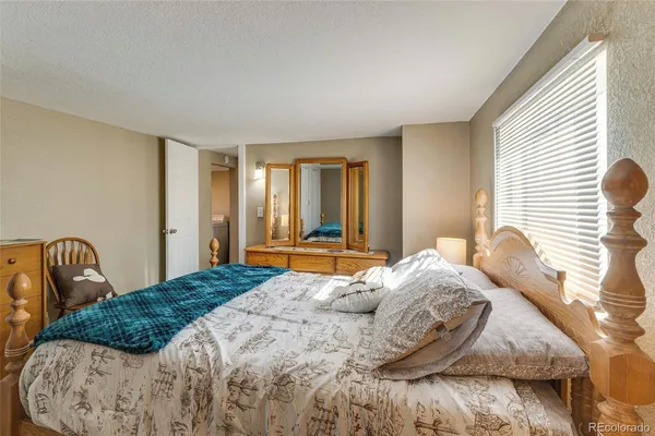a bedroom with a bed next to a window with chair