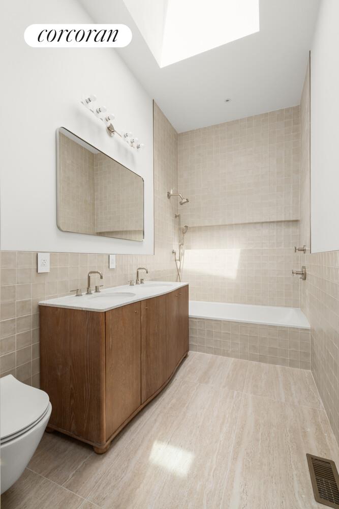700 Monroe Street Brooklyn, NY 11221 - Photo 13 of 18 a bathroom with a bathtub sink and mirror