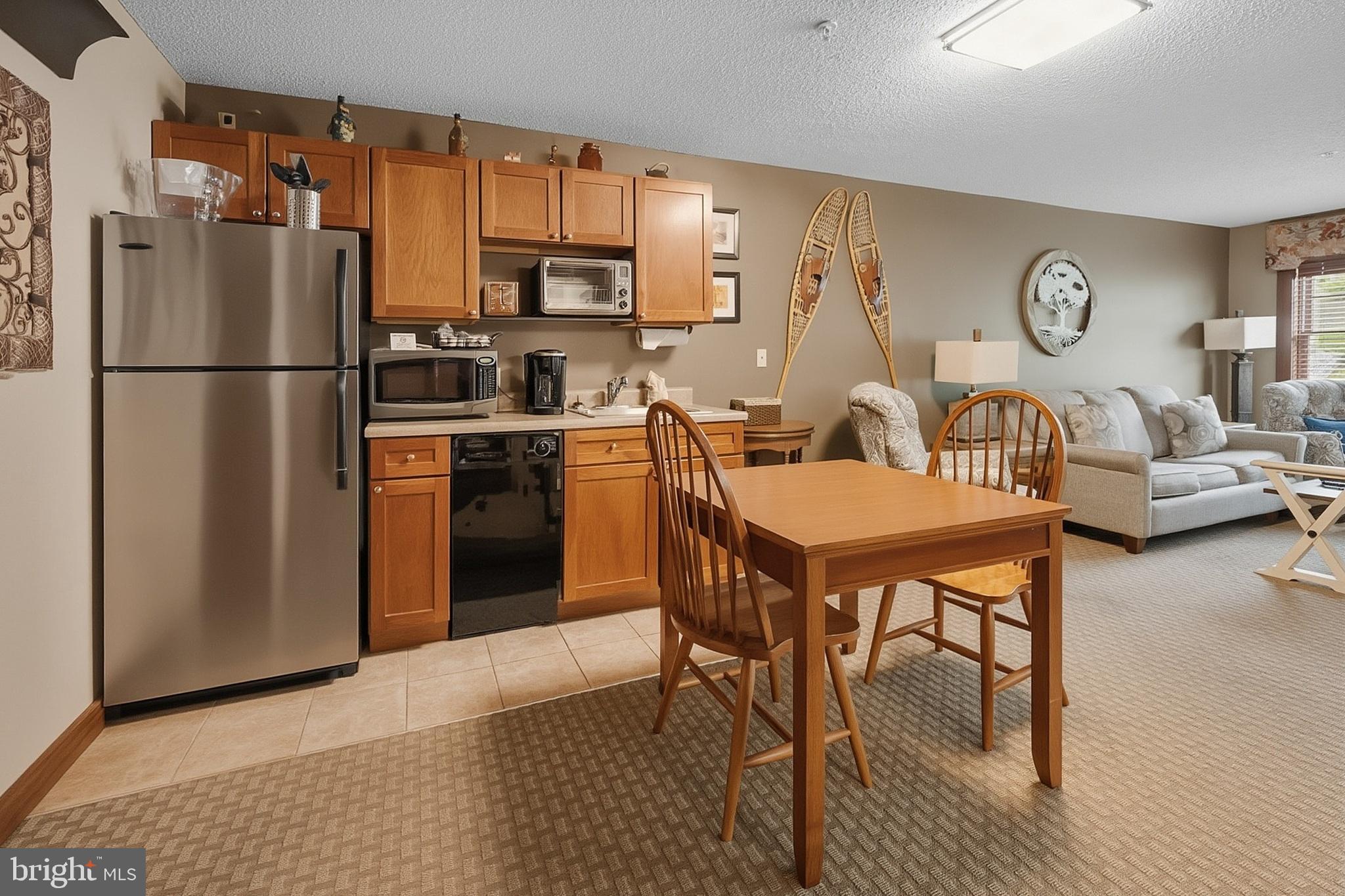 565 Glendale Road, Unit 208A Oakland, MD 21550 - Photo 11 of 51 a kitchen with stainless steel appliances granite countertop a dining table chairs refrigerator and sink