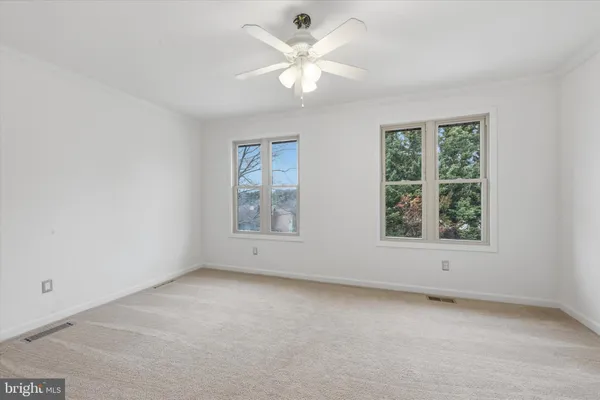 an empty room with chandelier fan and windows
