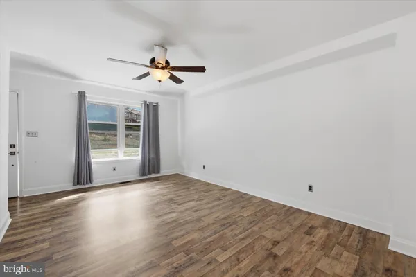 a view of a room with wooden floor and ceiling fan