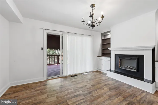 a view of a livingroom with a fireplace a chandelier and wooden floor