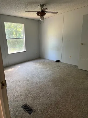 an empty room with windows and fan