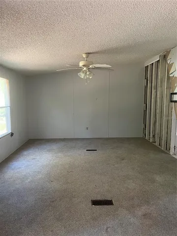 an empty room with a window and ceiling fan
