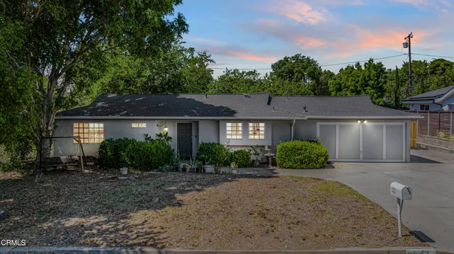 a front view of a house with a yard and potted plants