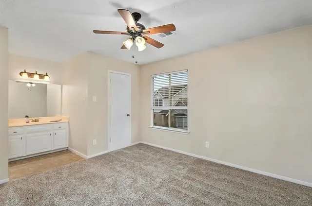 a view of a livingroom with a ceiling fan & a window