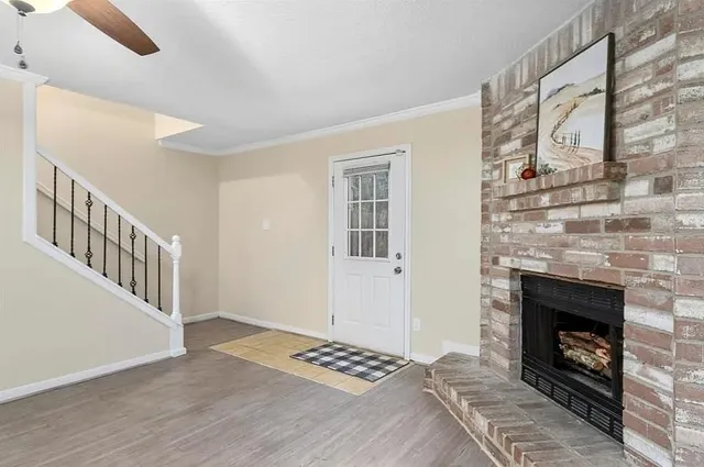 a view of an empty room with wooden floor fireplace and a window