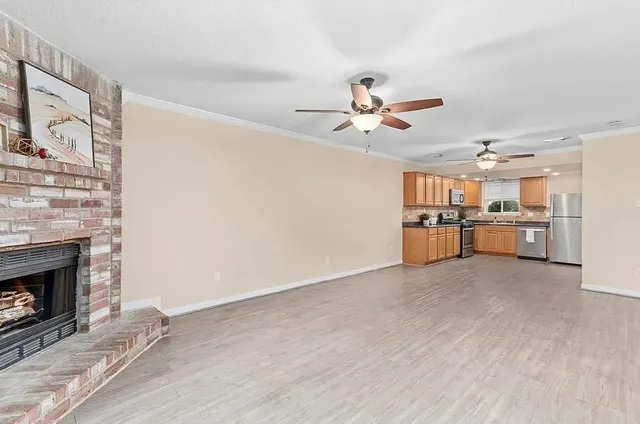 a view of a livingroom with a fireplace a ceiling fan and windows