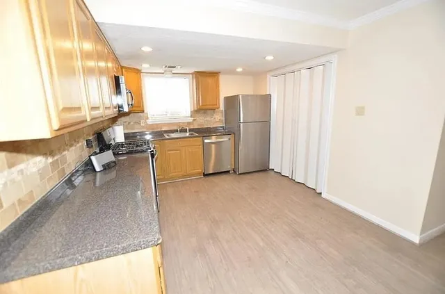 a open kitchen with stainless steel appliances granite countertop a refrigerator a oven a sink with island and couches