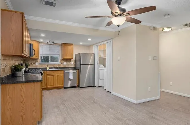 a kitchen with stainless steel appliances granite countertop a refrigerator a sink a stove a microwave oven with white cabinets