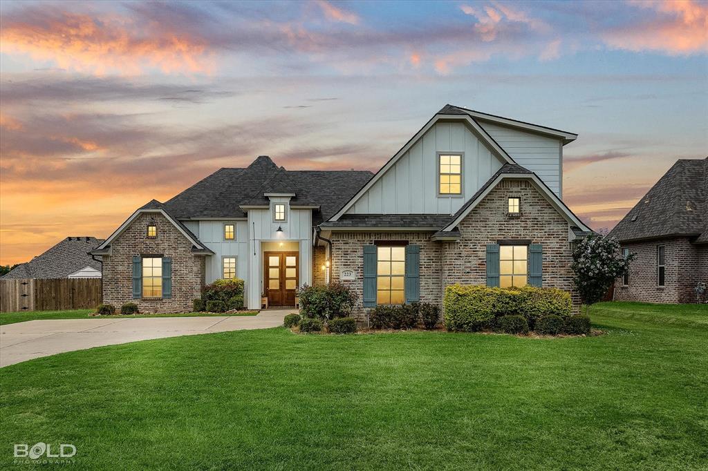 View of front facade featuring board and batten siding, french doors, brick siding, roof with shingles, and concrete driveway