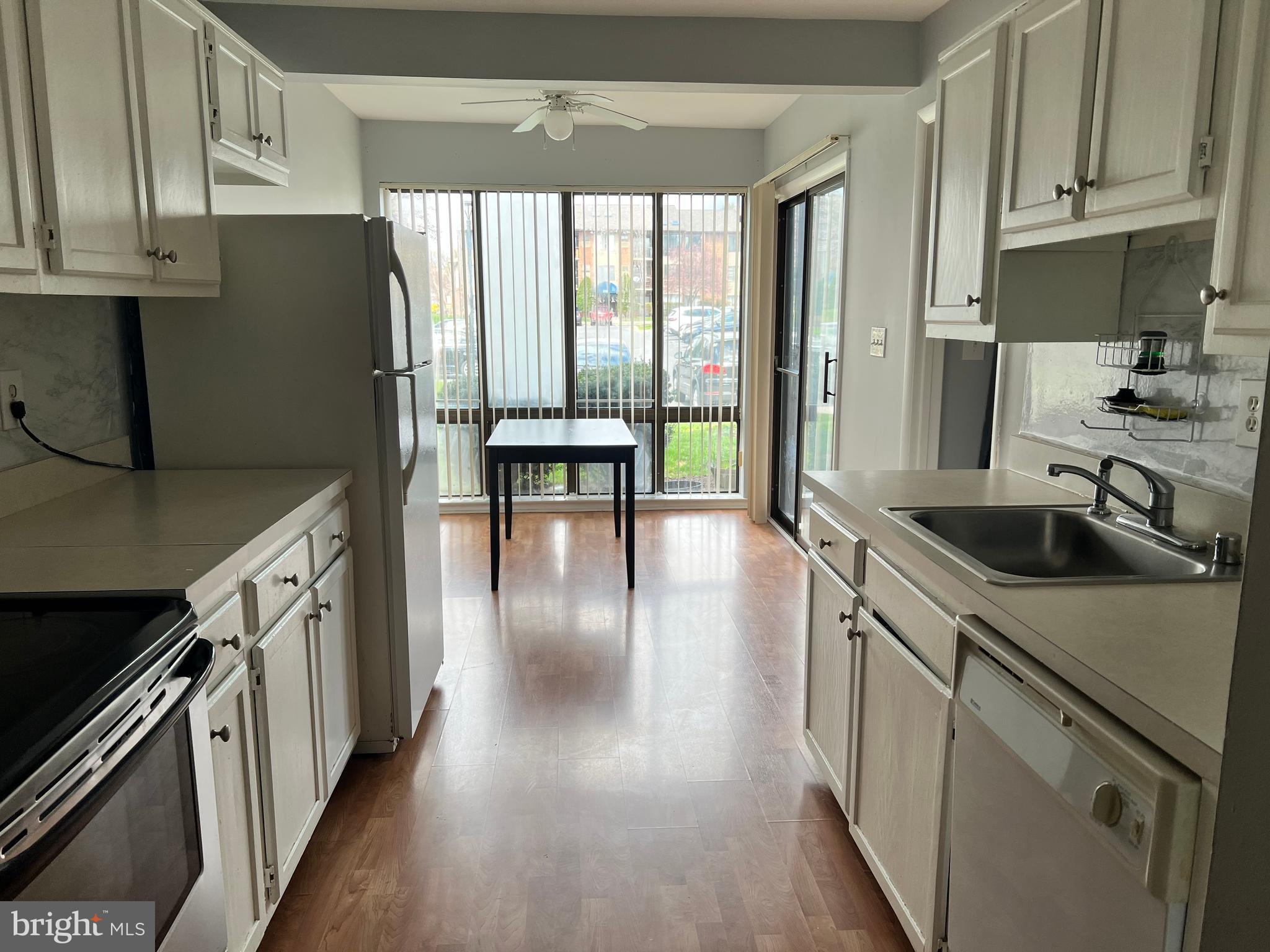 8141 Needwood Road, Unit 104 Derwood, MD 20855 - Photo 9 of 42 a kitchen with granite countertop a stove a sink a refrigerator and wooden floor