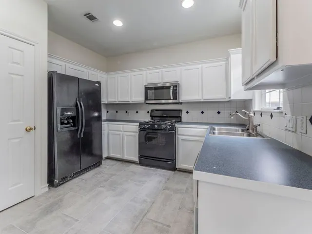 a kitchen with stainless steel appliances granite countertop a refrigerator sink and stove