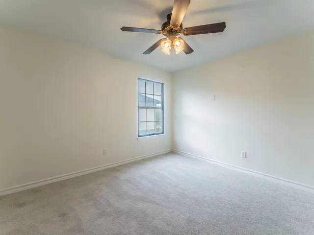 an empty room with a window and a fan