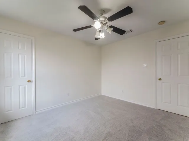 an empty room with a chandelier fan and closet area