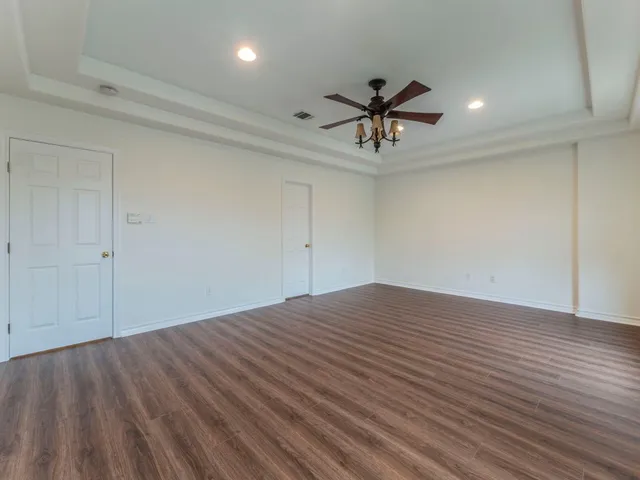 a view of empty room with wooden floor and ceiling fan