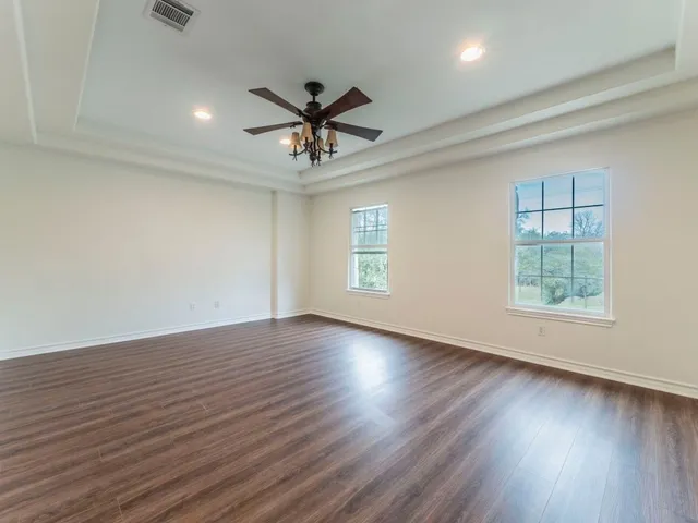 an empty room with wooden floor window and ceiling fan