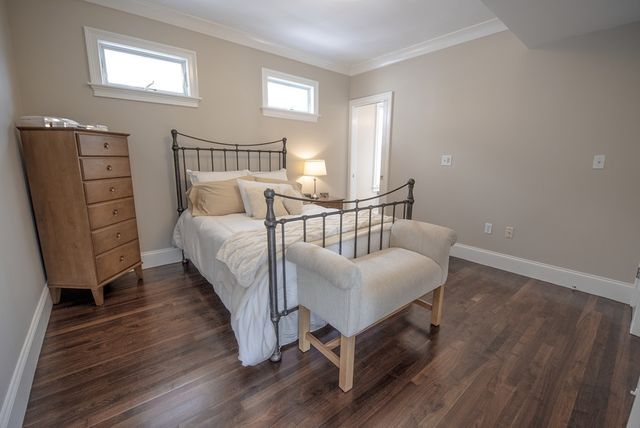 a bedroom with a bed next to a window with wooden floor