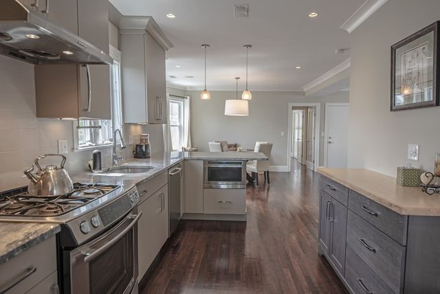 a kitchen with a stove a sink and wooden floor