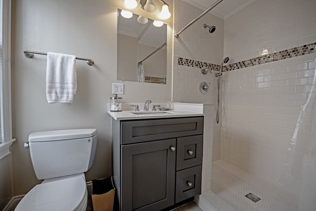 a bathroom with a sink a toilet a mirror and shower